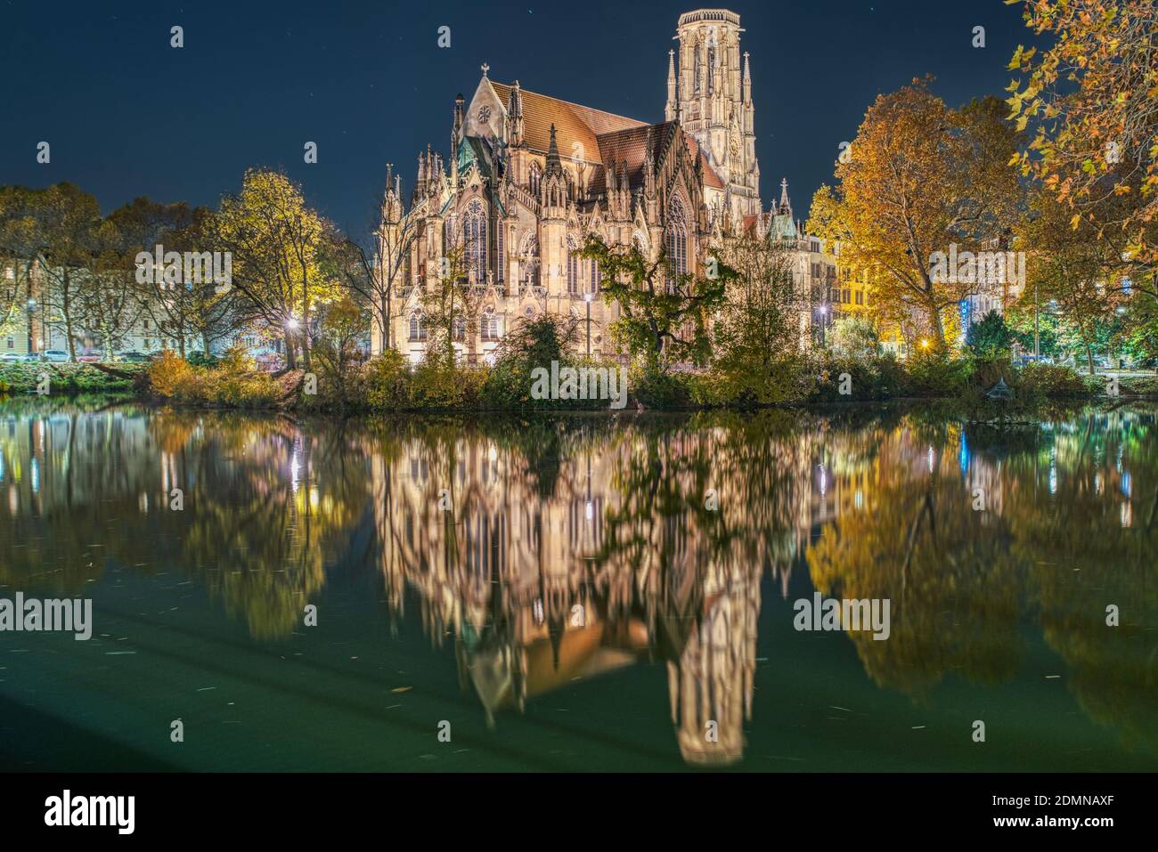 Johanneskirche Evangelische Johannesgemeinde Chiesa di notte in mezzo lussureggiante fogliame che si riflette sul lago Feuersee trasmette un concetto religioso. Stoccarda Foto Stock