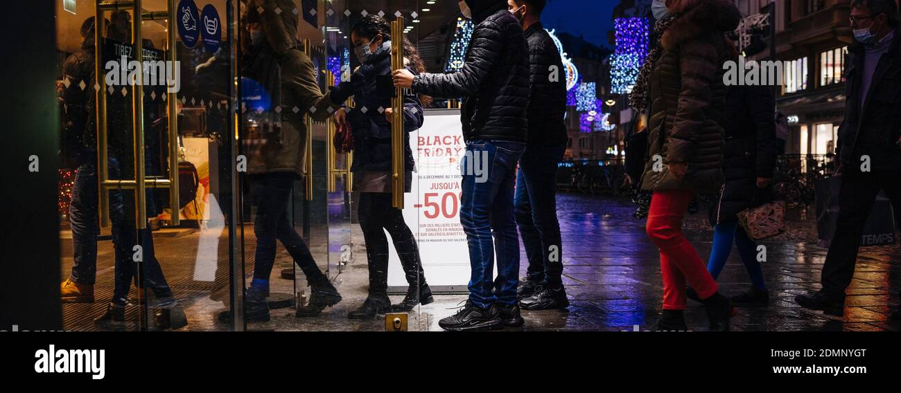 Strasburgo, Francia - 4 dicembre 2020: Ampia immagine di persone che entrano nel centro commerciale di notte con iscrizione sul banner d'ingresso - venerdì nero fino al 50% di sconto - natale decorato strada in background Foto Stock