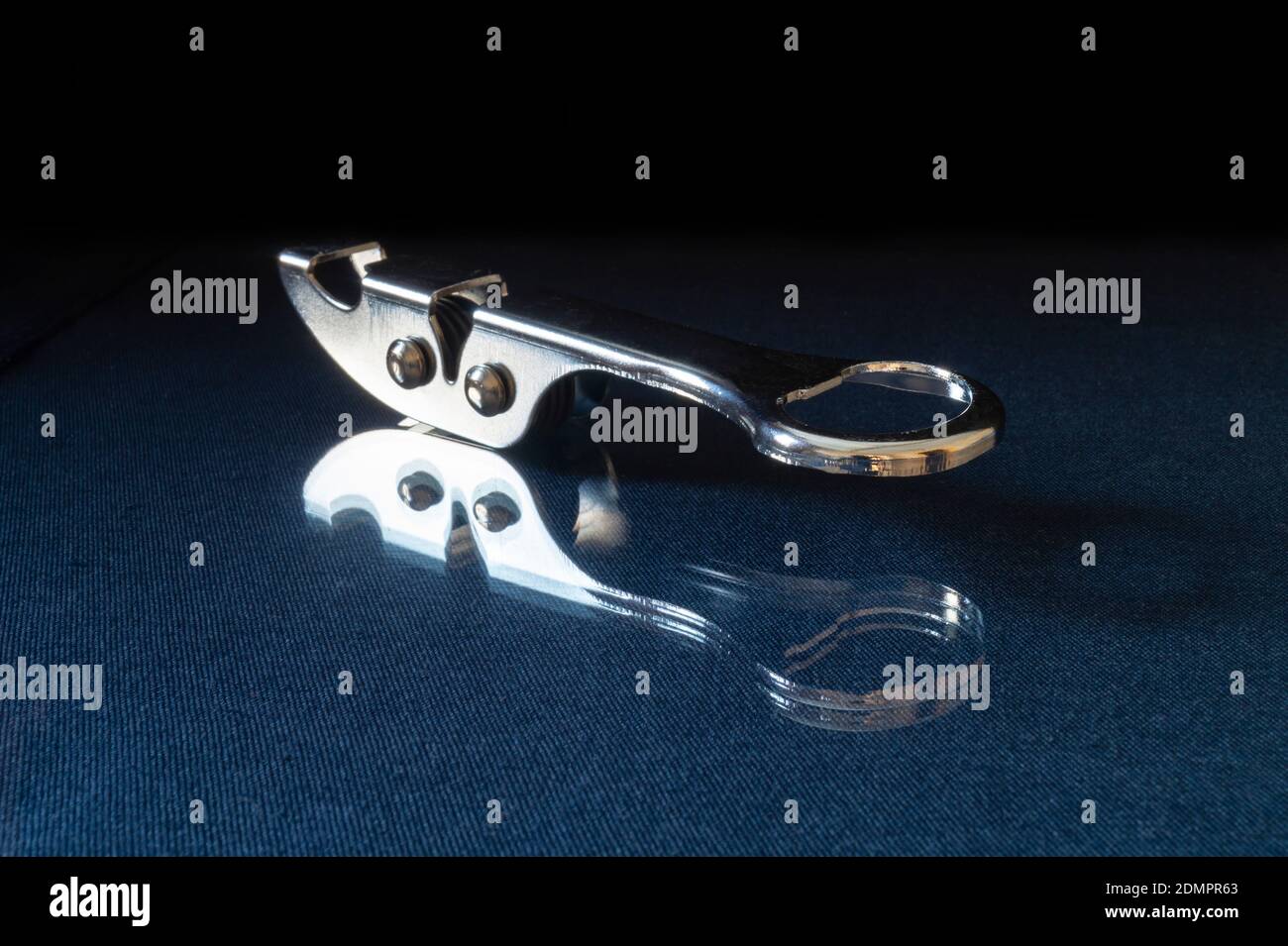 L'affilatura del coltello dagli acciai poggia su turn blu il tavolo con riflessione. Accessori da cucina su sfondo nero Foto Stock