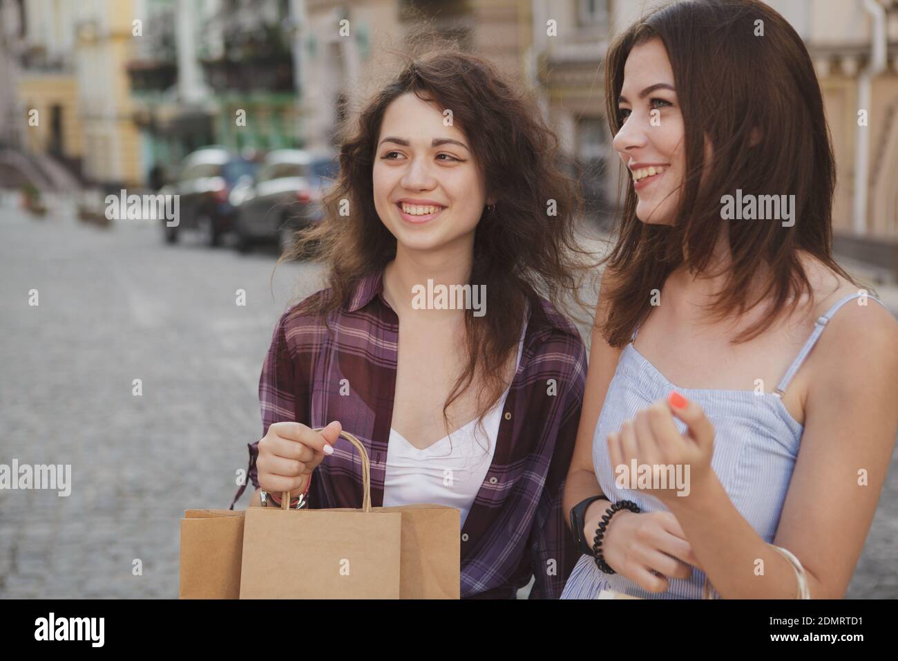 Felici le giovani amiche che ridono, camminano per le strade della città, trasportano borse per lo shopping. Vacanza, avvistamento, concetto di viaggio Foto Stock