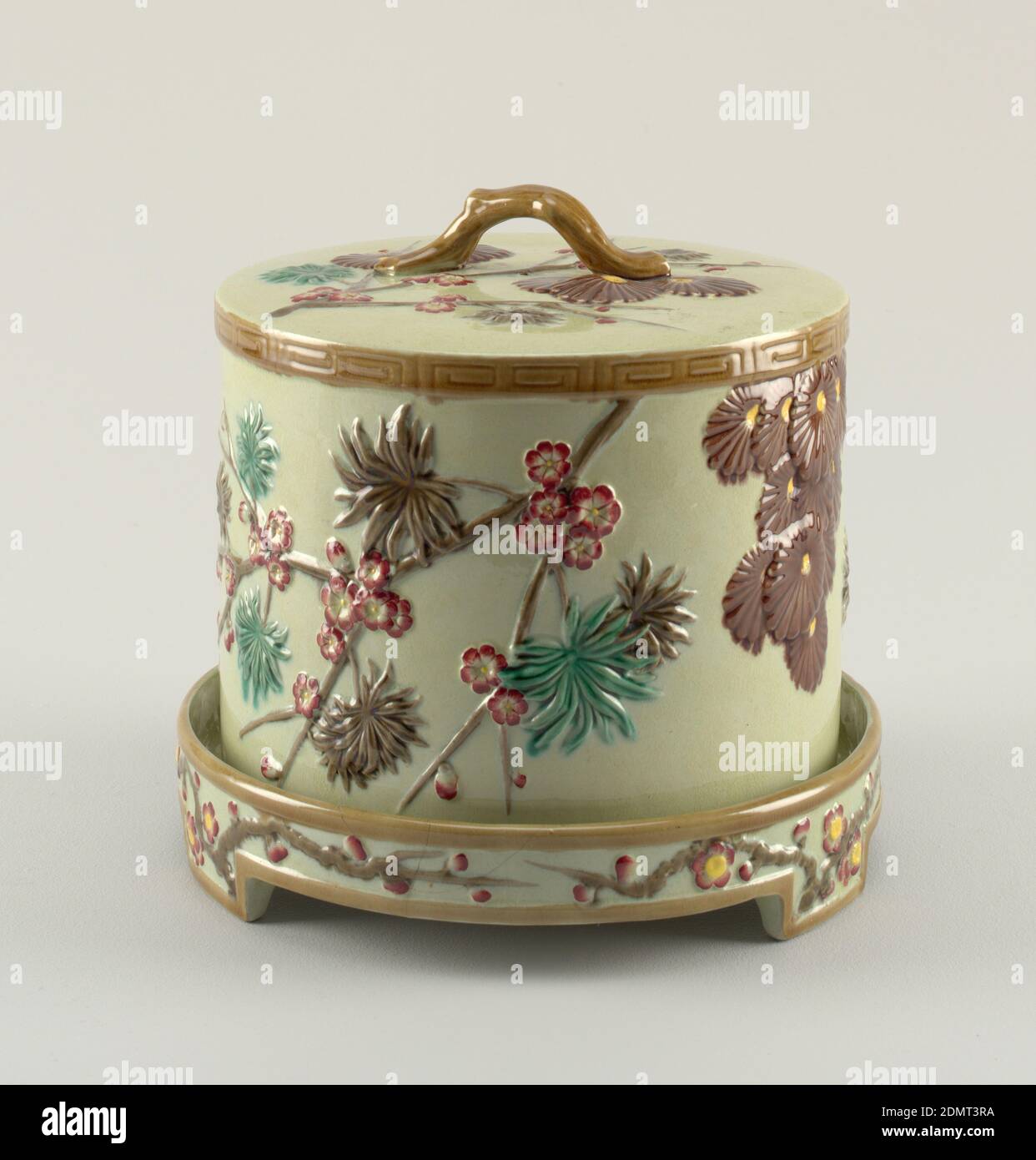 Piatto e coperchio, Wedgwood, inglese, stabilito 1759, modellato e smaltato terracotta ('maiolica'), A) campana cilindrica cava, diritto-laterale, piatto superiore. Stampato con rami fioriti asimmetrici in marrone con fiori rossi, foglie verdi e marroni, e con grappoli di crisantemi. La parte superiore della campana contiene un ornamento simile, con impugnatura a spirale applicata. B) piatto adattato per ospitare copertura, su tre piedi, decorato al confine con rami e fiori., Inghilterra, ca. 1880, ceramica, arti decorative, piatto e copertina Foto Stock