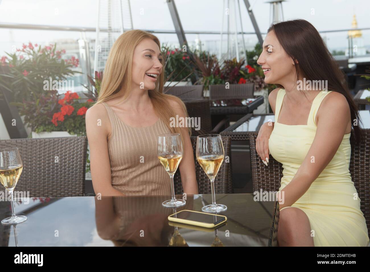 Belle ed eleganti donne che chiacchierano con un bicchiere di vino all'aperto ristorante Foto Stock