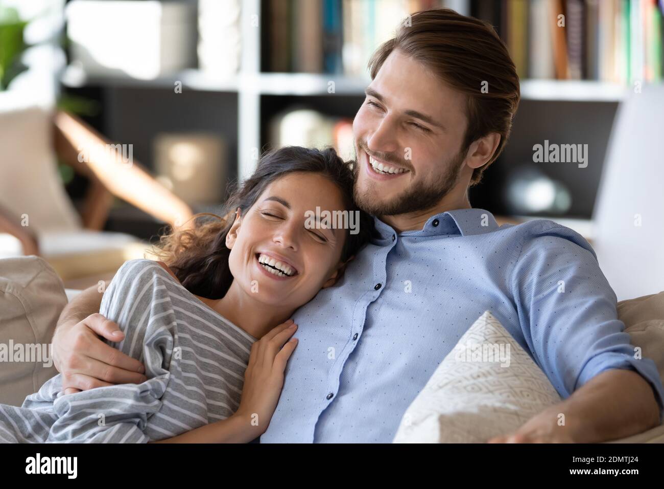 Felice giovane coppia rilassarsi sul divano hugging Foto Stock