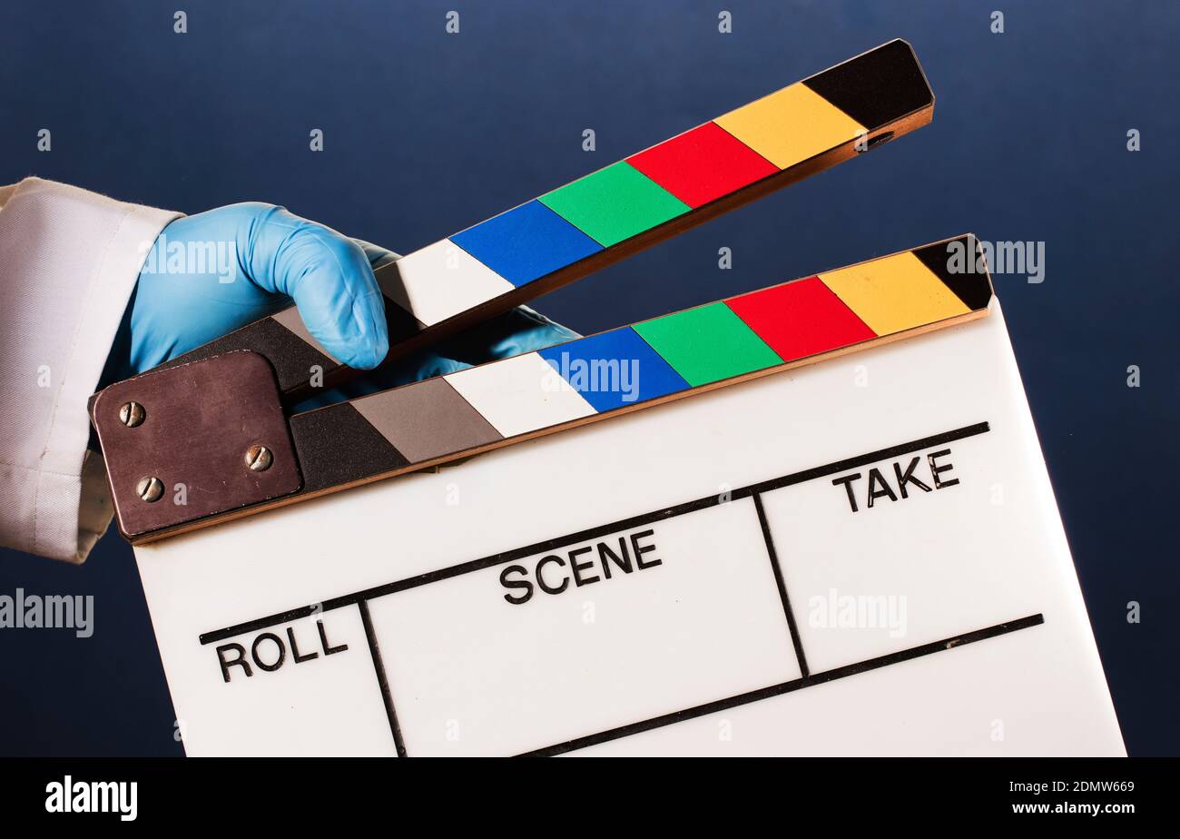 medico in guanti chirurgici blu che tengono clapperboard film, sfondo bianco (parole, rotolo, scena, prendere) regista, Foto Stock