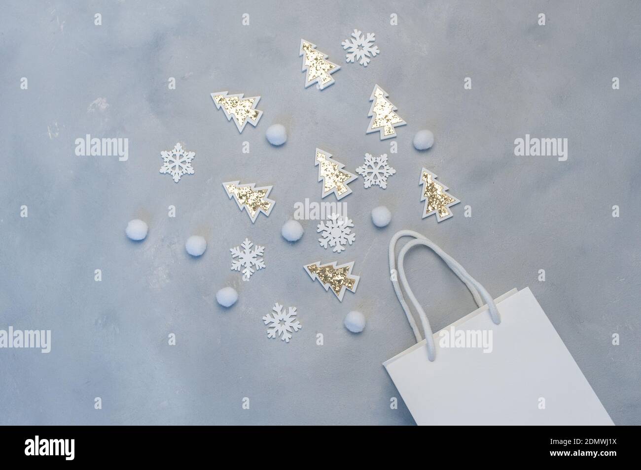 Concetto di shopping mockup di Natale. Pacchetto bianco Kraft con fiocchi di neve e abete con posto per il tuo testo su sfondo grigio. New Year Flat Lay Foto Stock