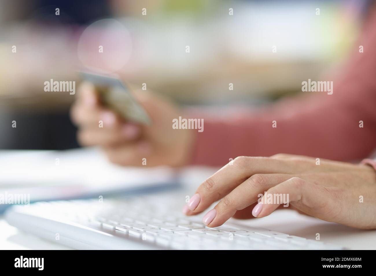 Mano femminile sulla tastiera in seconda mano tenendo credito carta bancaria Foto Stock