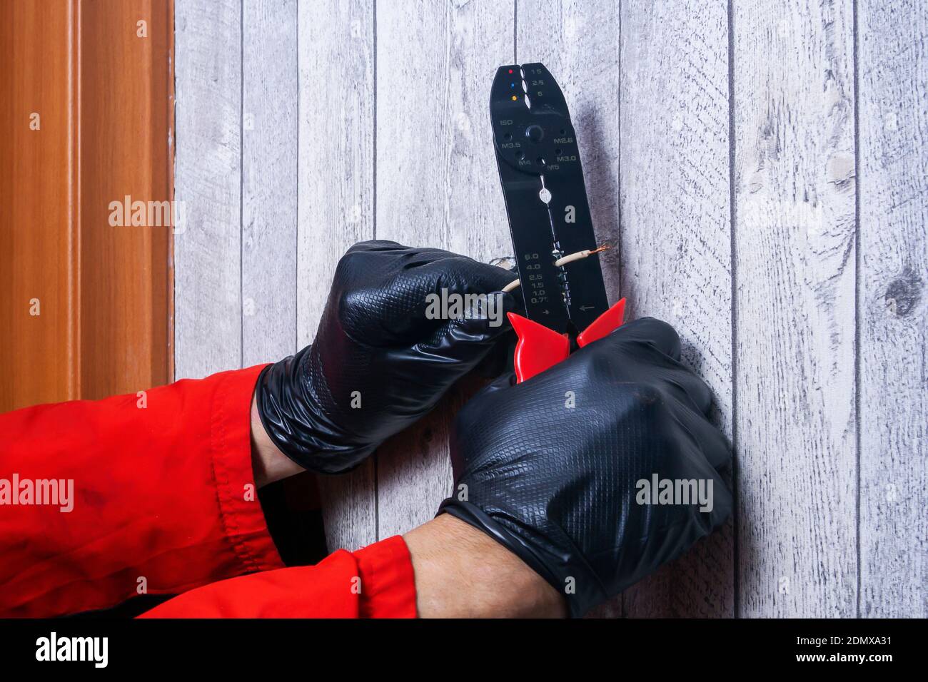 l'elettricista pulisce il filo dalla treccia per il collegamento la presa Foto Stock