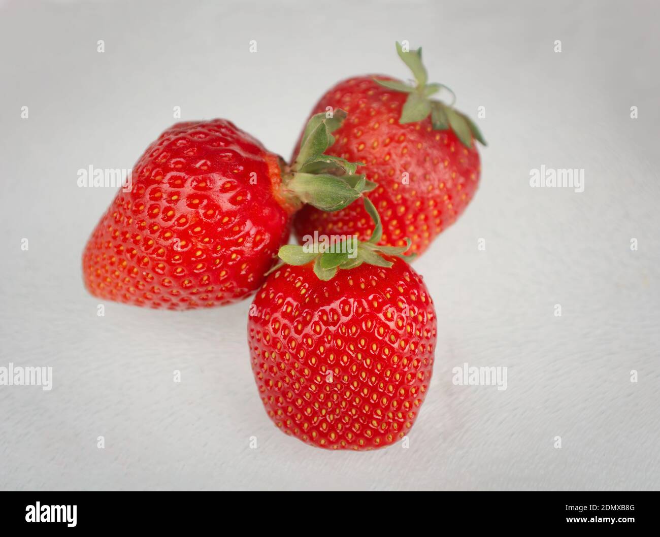 Tre le fragole su sfondo bianco Foto Stock