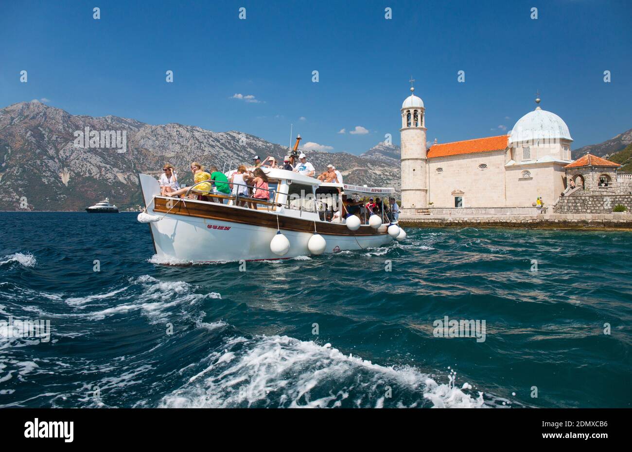 Perast, Cattaro, Montenegro. Barca che parte attraverso la baia di Cattaro dalla Chiesa di nostra Signora delle rocce. Foto Stock