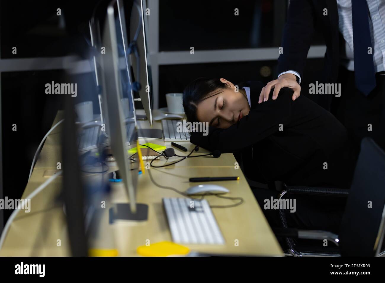 Il responsabile si trova dietro ai dipendenti che dormivano segretamente durante l'orario di lavoro in ufficio di notte. Foto Stock