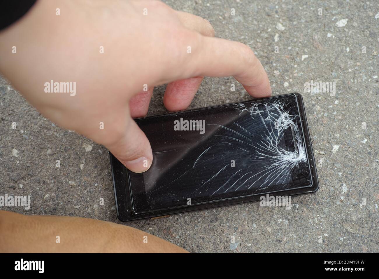 Una persona che raccoglie uno smartphone rotto caduto. Smartphone con schermo rotto. Primo piano. Foto Stock