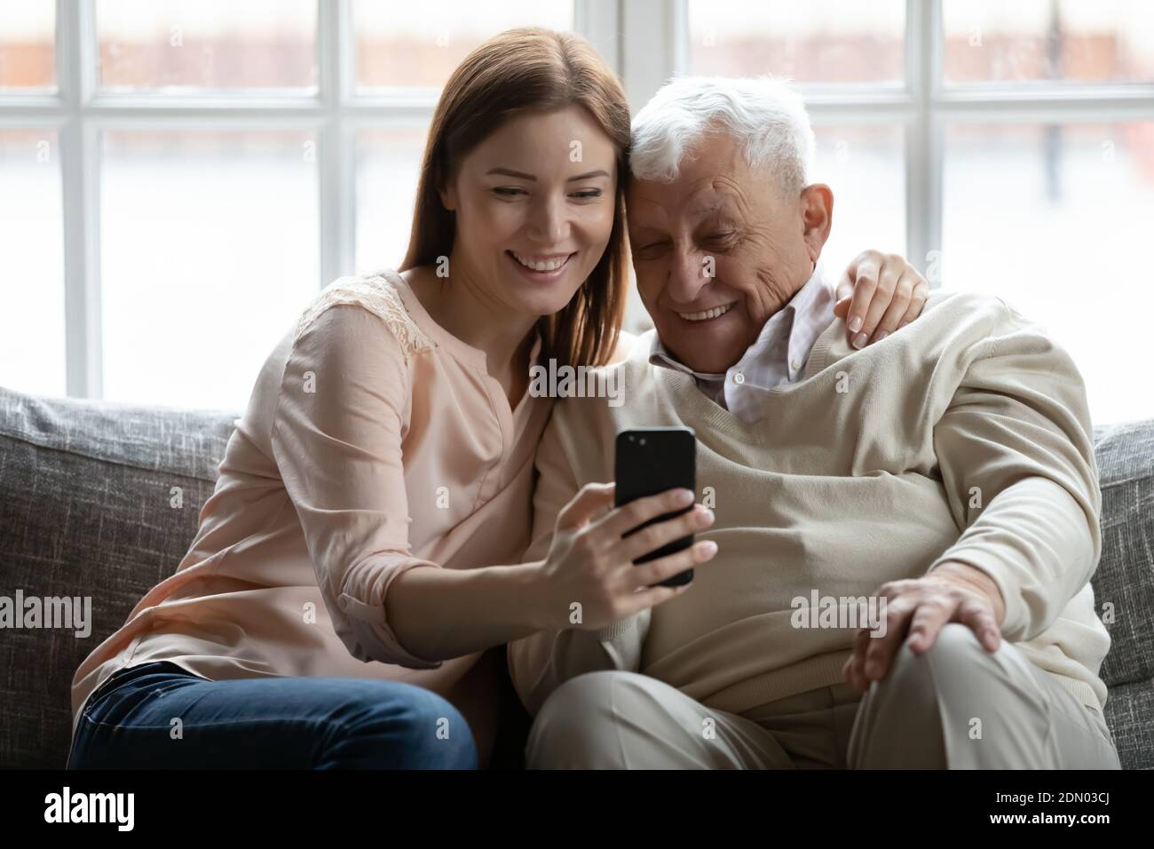 nipote adulta che ama prendere selfie al telefono abbracciando nonno anziano Foto Stock