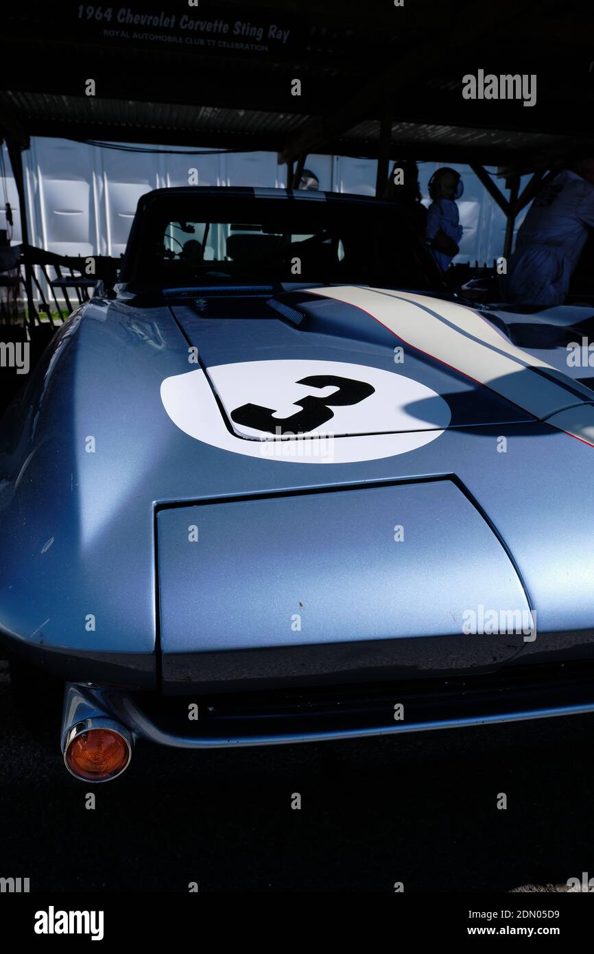 La forma distintiva di una Chevrolet Corvette Stingray degli anni '60 esce dalle ombre del paddock al Goodwood Revival 2019. Foto Stock