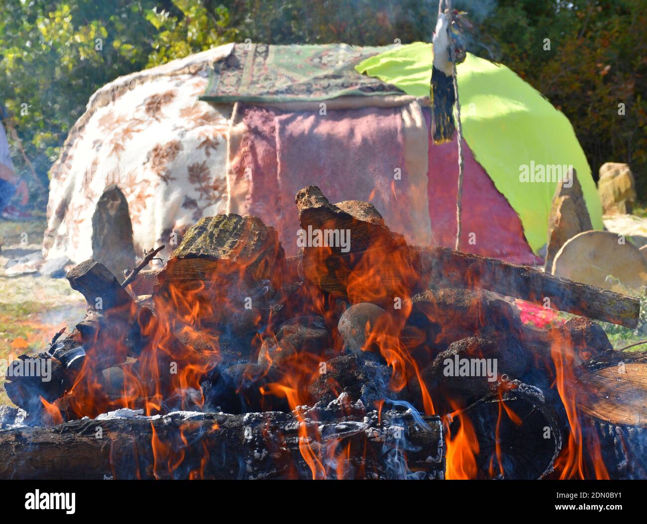 Falò con pietre e inipi ricoperti di coperte sullo sfondo. Foto Stock