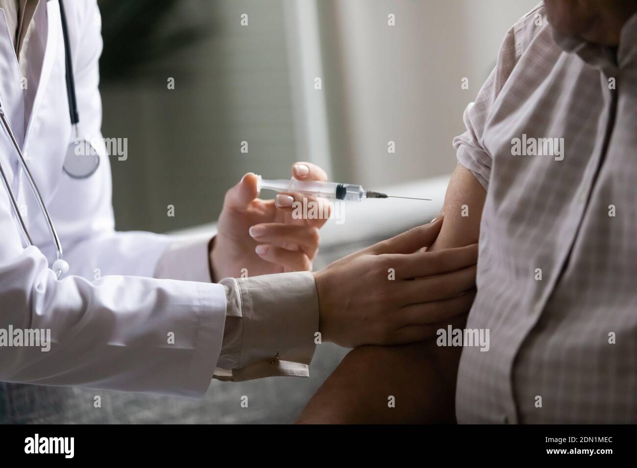 Mani di lavoratore medico che iniettano la dose di farmaco al braccio del paziente Foto Stock