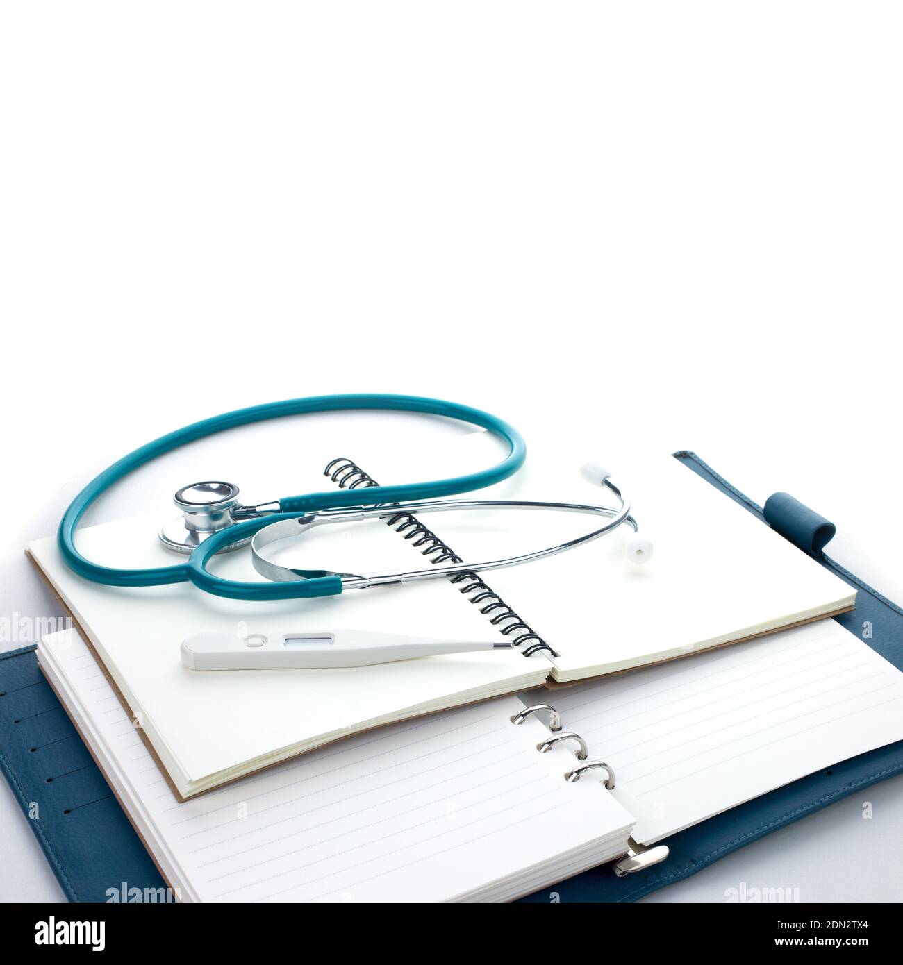 Vista ad angolo alto dello stetoscopio con diari su sfondo bianco Foto Stock