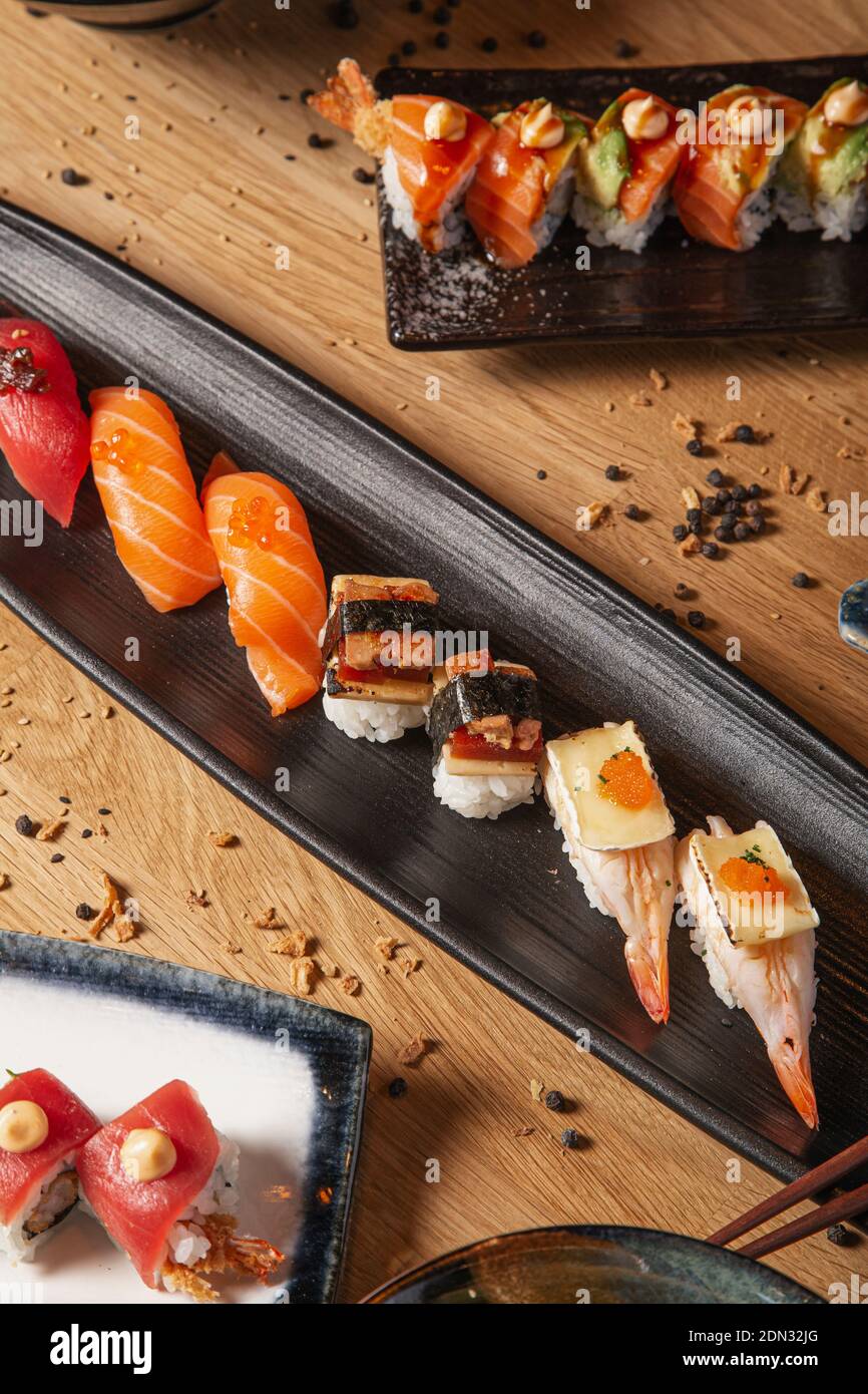 Varietà di sushi e nigiri sul tavolo serviti in piatti di ceramica. Foto Stock