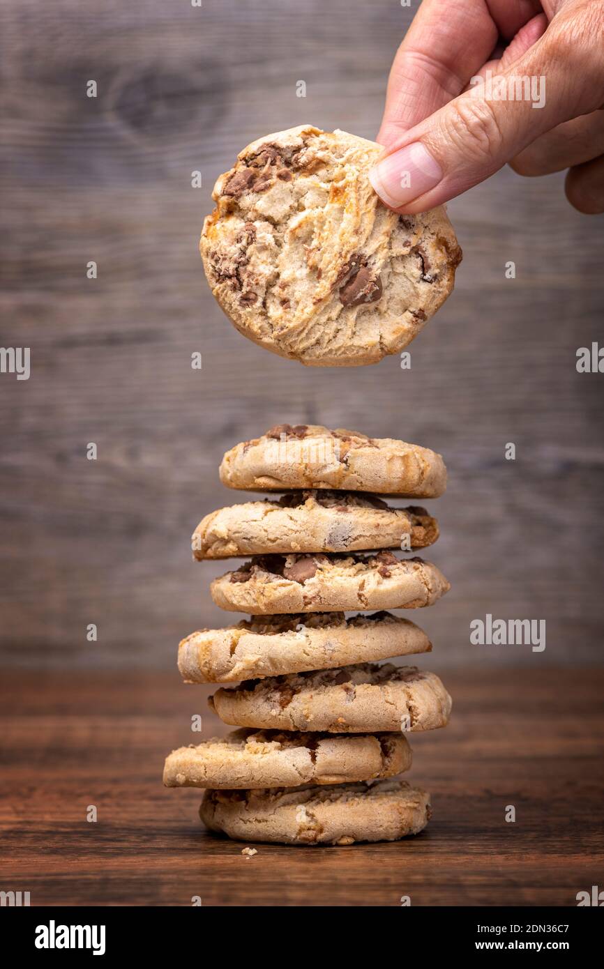 Human hand taking a chocolate chip cookie cookie from a stack Foto Stock
