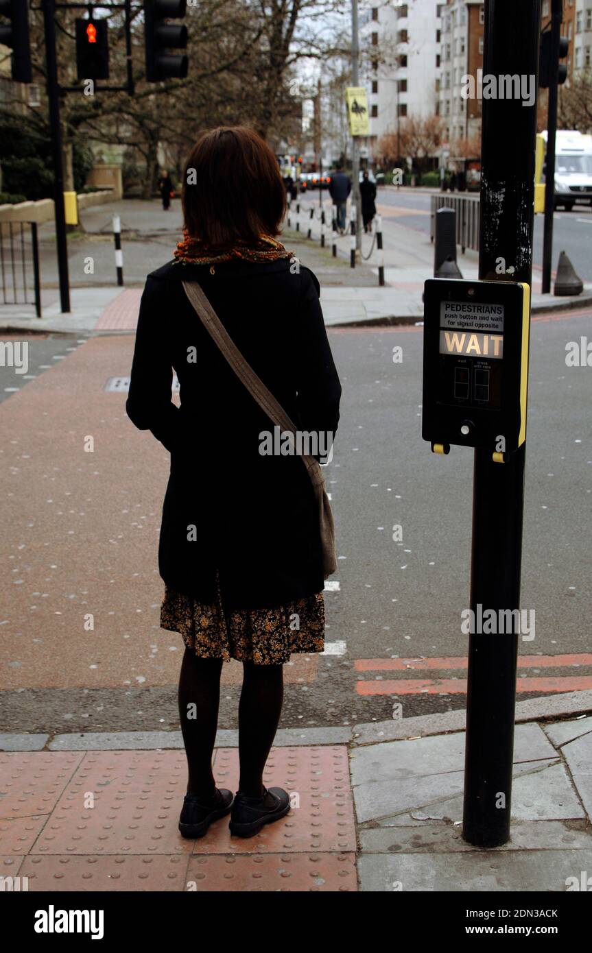 Donna in attesa di attraversare la strada. Hampstead. Londra, Inghilterra, Regno Unito. Foto Stock