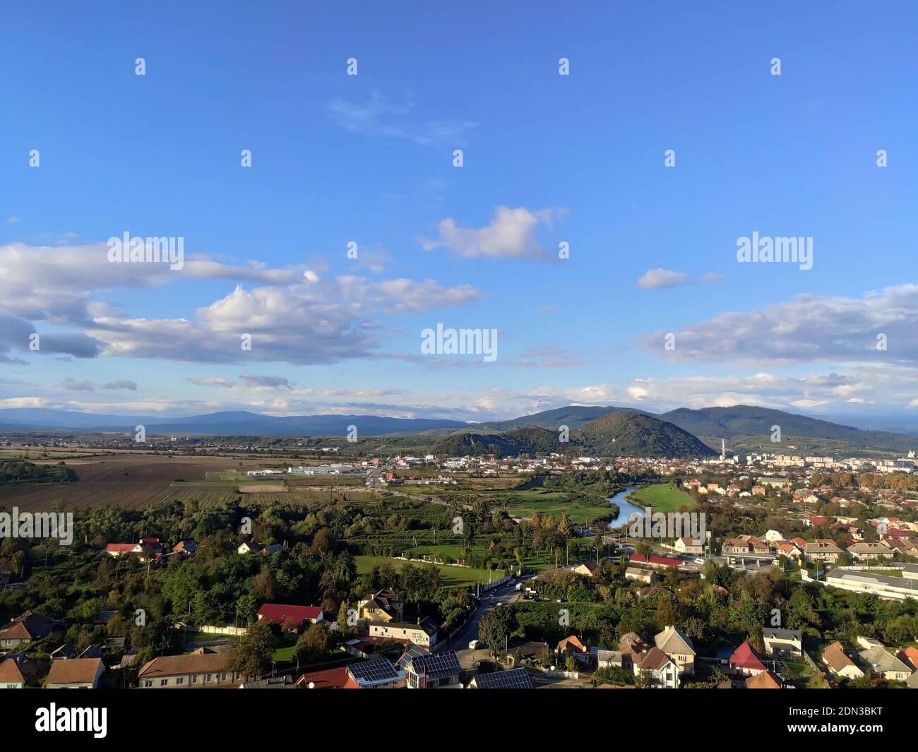 Piccola città europea con un piccolo fiume sullo sfondo di basse montagne nel luminoso giorno d'autunno Foto Stock