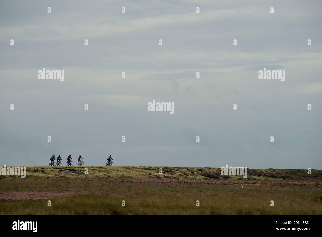 Un piccolo gruppo di cinque ciclisti che attraversano la brughiera Traccia del modo Waskerly Foto Stock
