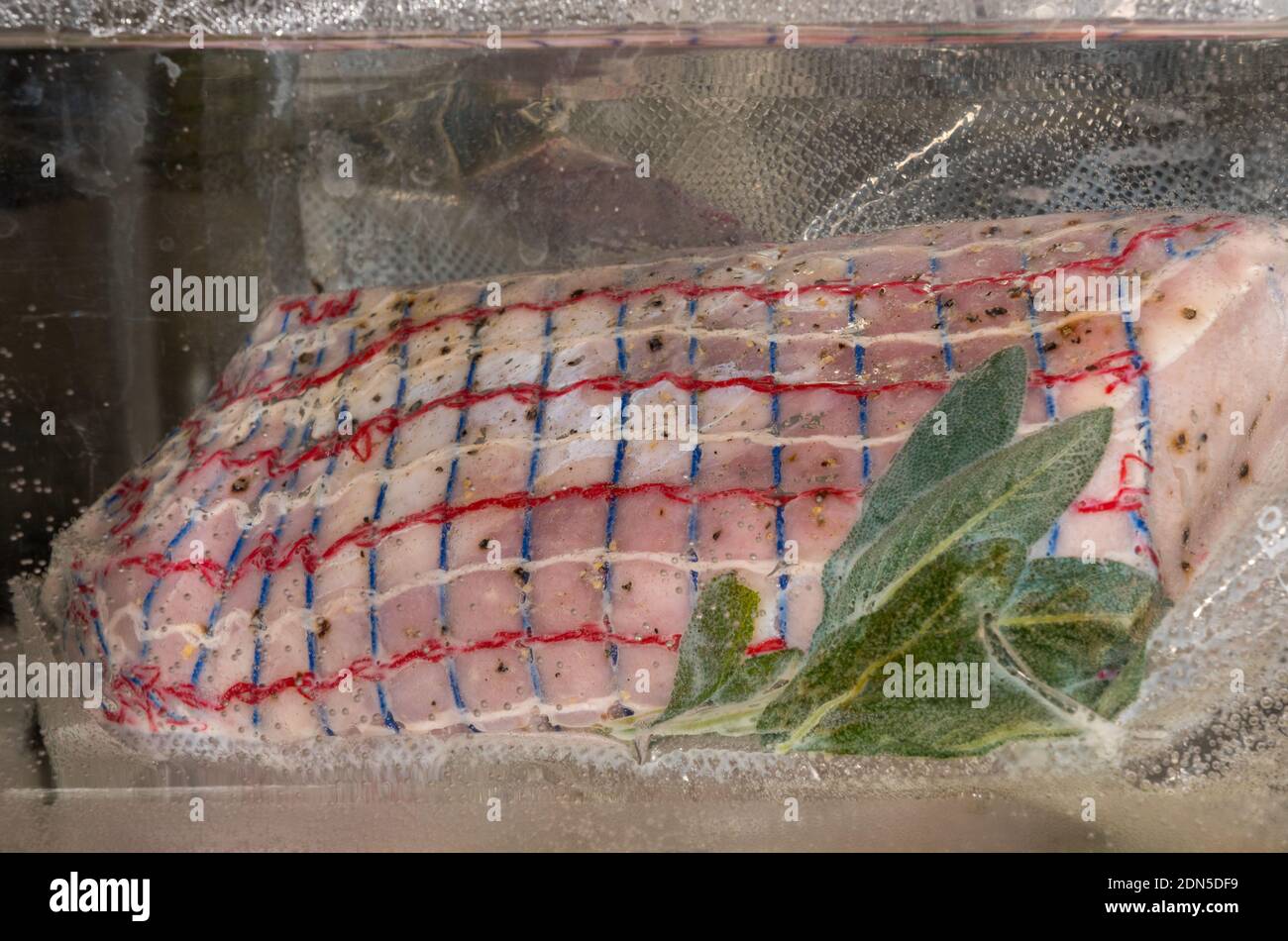 Sous vide bagno d'acqua che tiene un filetto di maiale all'interno di a. sacchetto di plastica sigillato sottovuoto per la cottura Foto Stock