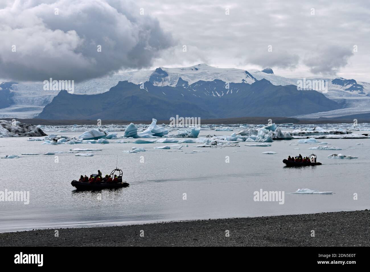 Due barche zodiacche durante un tour della laguna glaciale di Jokulsarlon nell'Islanda del Sud. I ghiacciai si possono vedere sulle montagne e gli iceberg galleggiano sul lago. Foto Stock