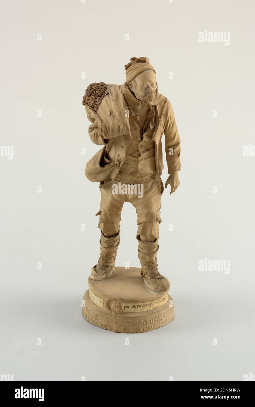 Venditore di Cicorie, Angelo Leone, Terracotta, figura maschile a strisce su base circolare. Con bearded. Porta un sacco di cicoria sulla spalla destra. Cappuccio e bandana copri testa e collo. Camicia e maglia aperte al collo. Cappotto sbottonato. Borsa sulla spalla destra. Ginocchiere e sottabiti con bottoni visibili. Leggings e sandali., Catania, Sicilia, Italia, dopo il 1873, ceramica, Arti decorative, Figura, Figura Foto Stock
