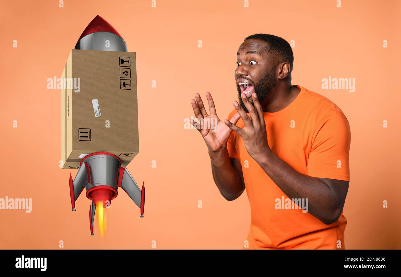 Stupito e sconvolto espressione di un ragazzo che riceve un pacchetto. Sfondo arancione Foto Stock