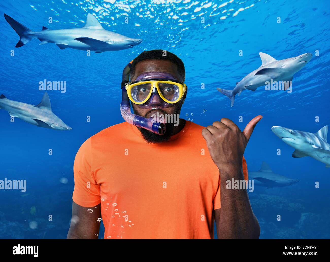 Uomo scottato con maschera subacquea circondata da squali Foto Stock