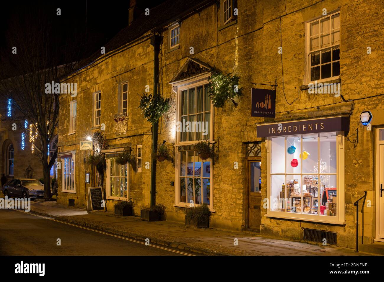 Negozi di alta strada con decorazioni natalizie di notte. Woodstock, Oxfordshire, Inghilterra Foto Stock