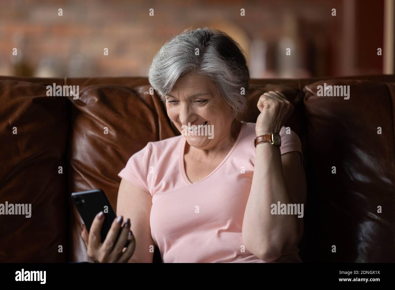Donna euforica matura anni '60 che guarda lo schermo dello smartphone Foto  stock - Alamy