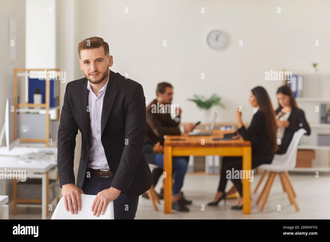 Bel responsabile vendite dell'azienda che si trova in uno spazio di lavoro moderno ufficio cercando alla telecamera Foto Stock