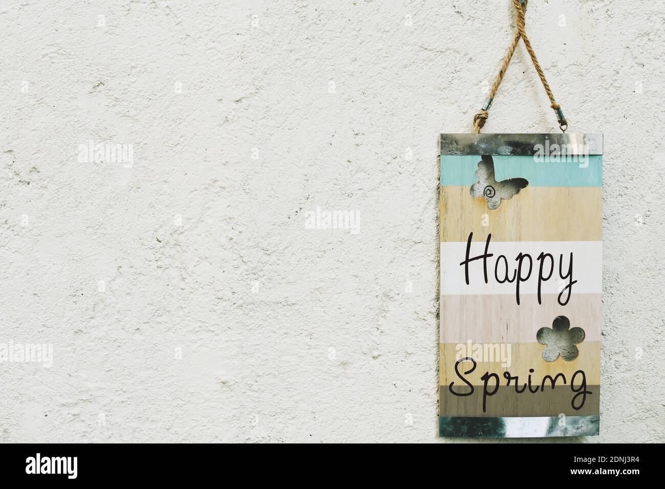 Felice primavera scritta su una tavola di legno appesa su un muro. Spazio di copia. Foto Stock