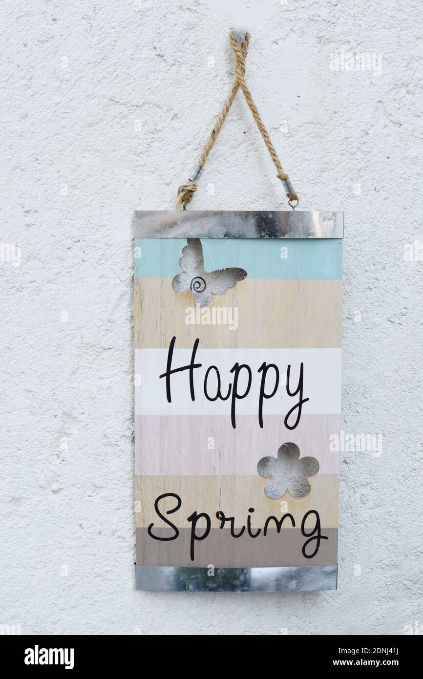 Felice primavera scritta su una tavola di legno appesa su un muro. Foto Stock