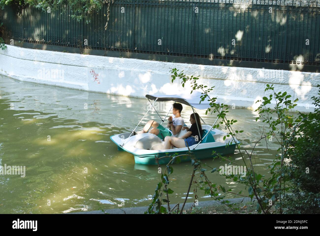 Giovane coppia seduta in idro-bicicletta e giro sul lago nel parco di Cismigiu. Foto Stock