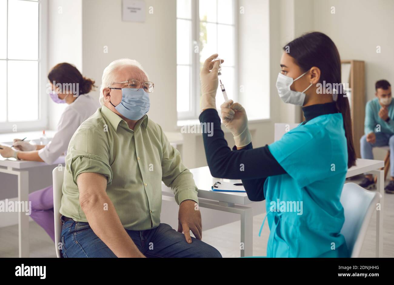 Paziente anziano in attesa di ottenere un colpo e guardare giovane medico che prepara il vaccino Foto Stock