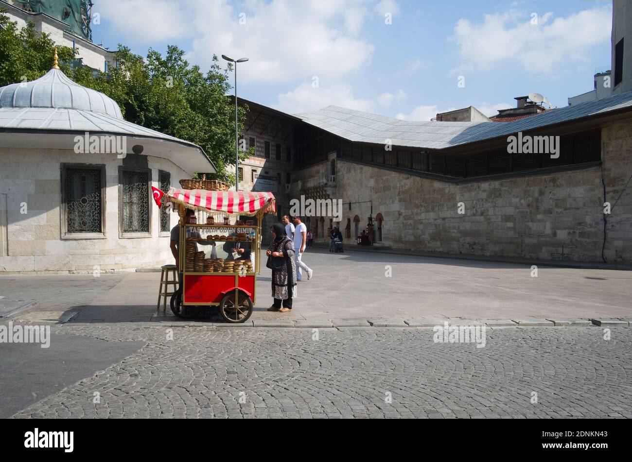 Istanbul, Turchia - Settembre, 2018: Uomo che vende orbagel di pane turco circolare simit dal tradizionale venditore rosso su ruote. Parte della cultura del fast food Foto Stock