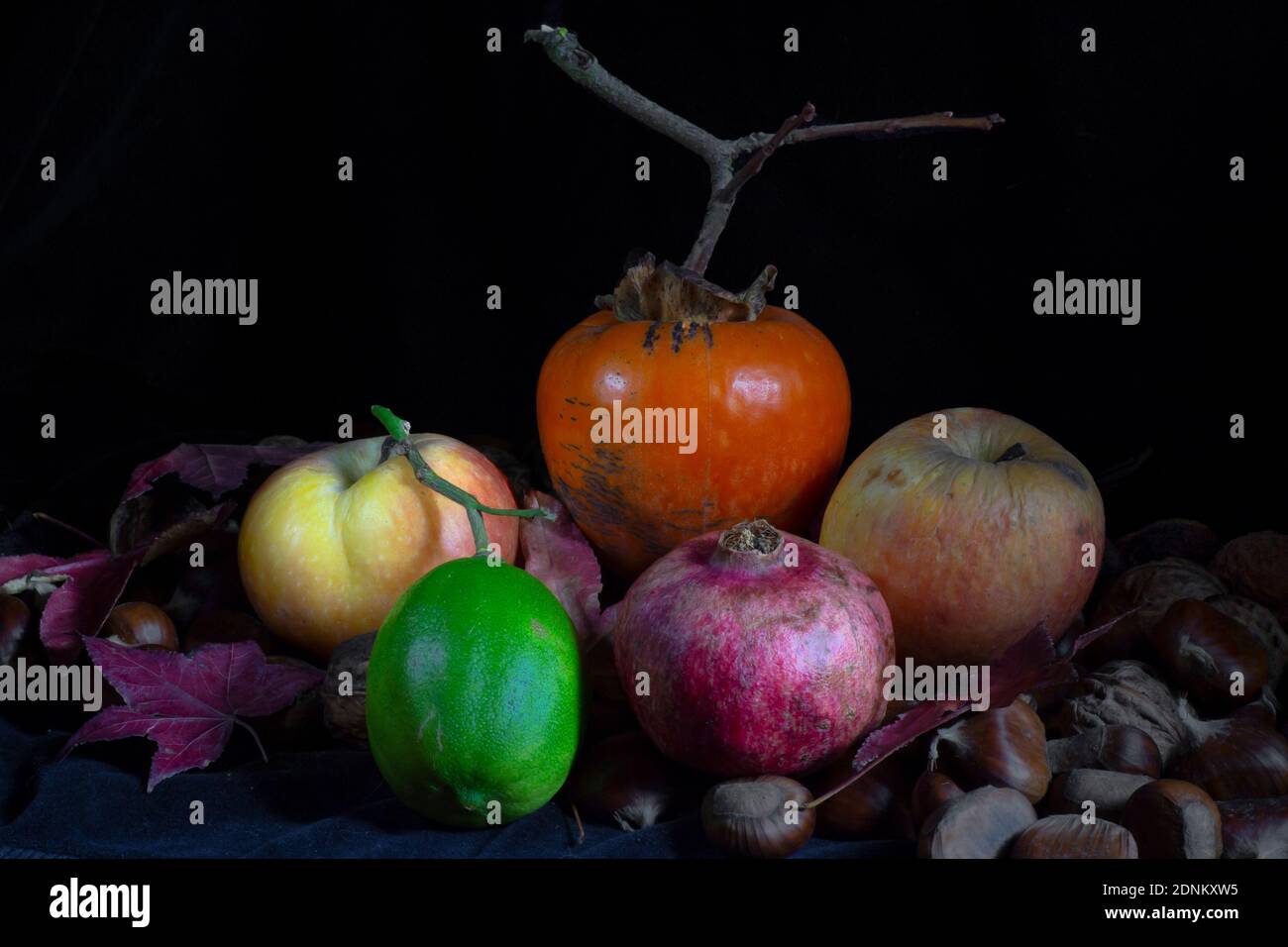 composizione mista di frutta d'autunno e limone verde un piano e uno sfondo scuri Foto Stock