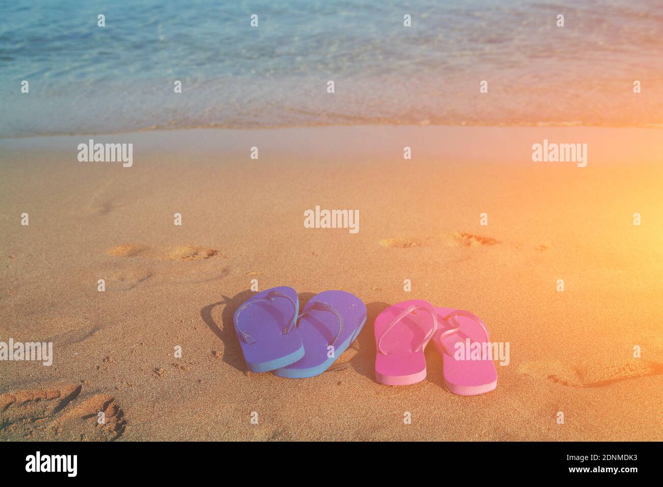 Romantica spiaggia scena. Maschi e femmine di flip flop sandals sulla spiaggia di sunrise Foto Stock