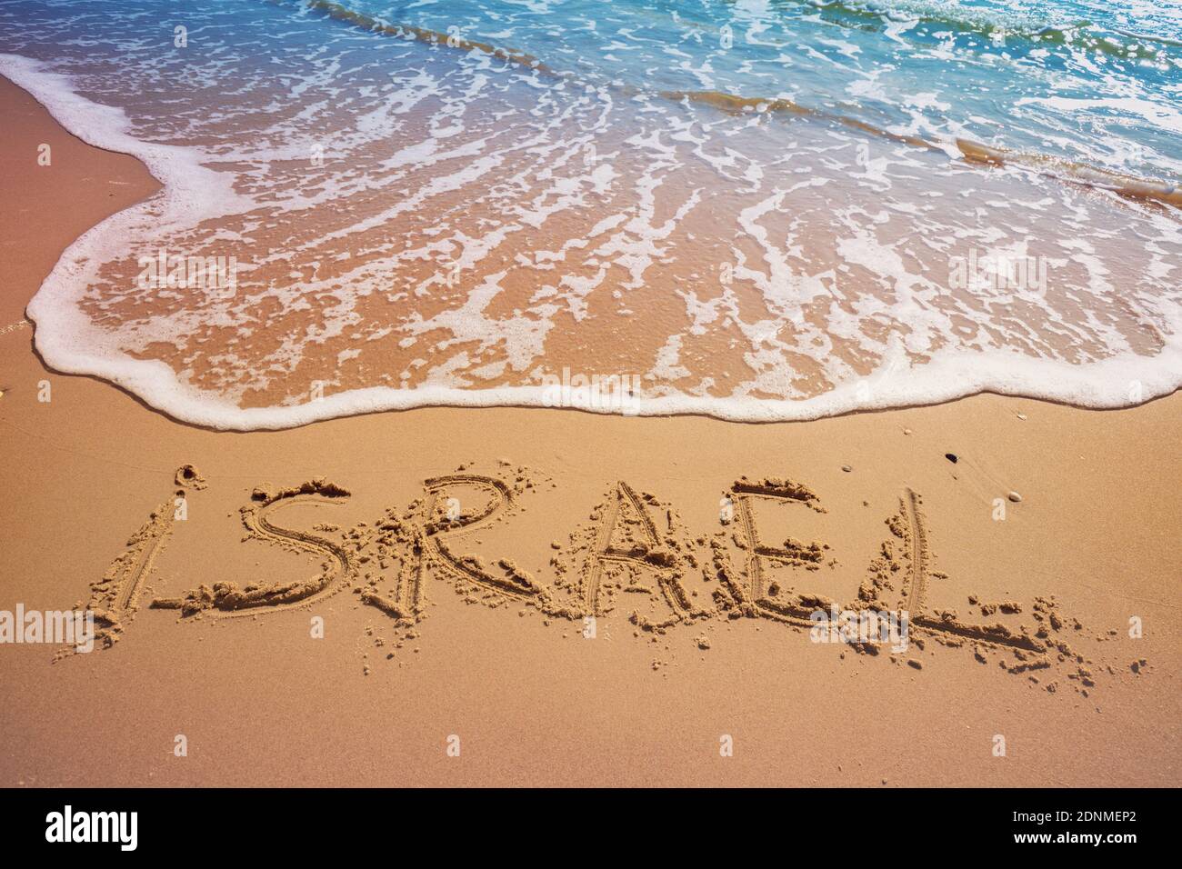 La parola Israele sulla spiaggia di sabbia. Iscrizione Israele sul mare con un'onda Foto Stock