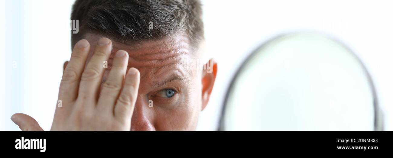 L'uomo sta modellando i suoi capelli con il gel davanti allo specchio. Foto Stock