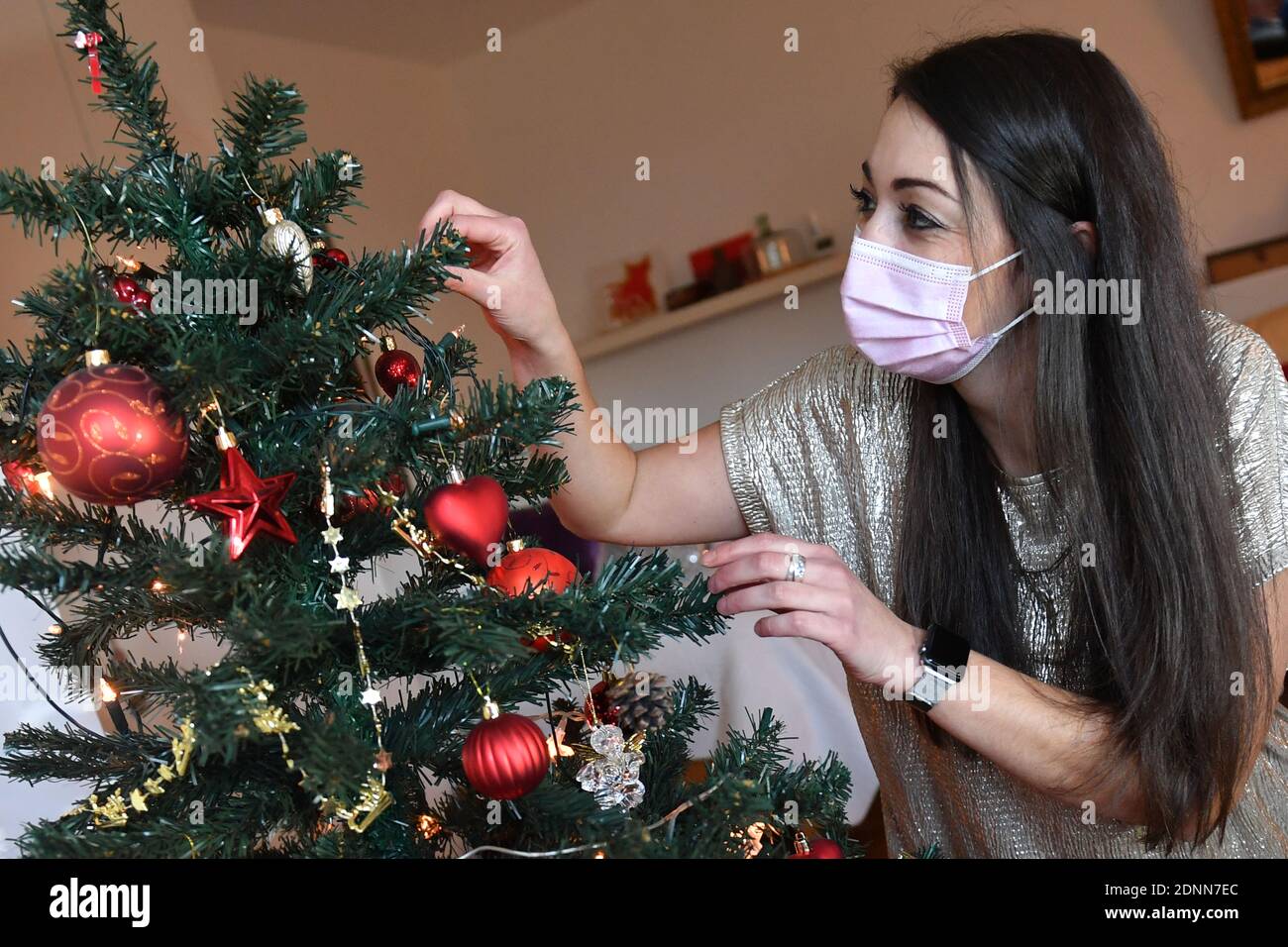 Monaco, Germania. 17 Dicembre 2020. Topic picture Lonely Weihafterten 2020 nella pandemia del coronavirus: Una giovane donna con maschera facciale, maschera decorare la sua Weihaftertsbaum. Pandemia, blocco, arresto, valore di incidenza. MODELLO RILASCIATO! | utilizzo in tutto il mondo credito: dpa/Alamy Live News Foto Stock