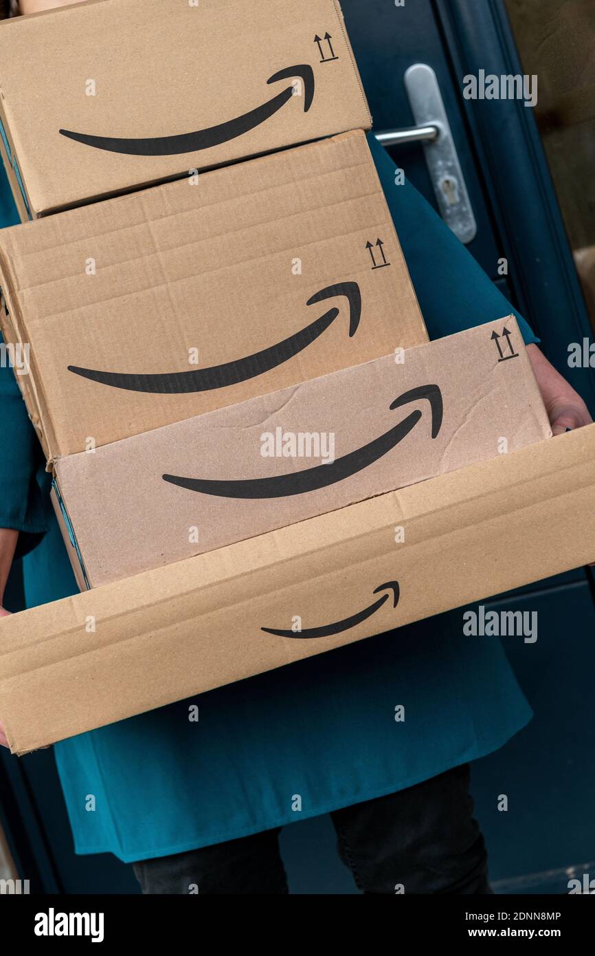 Lille, Francia - 18 dicembre 2020 : donna che trasporta i pacchetti di amazon davanti all'entrata della sua casa Foto Stock