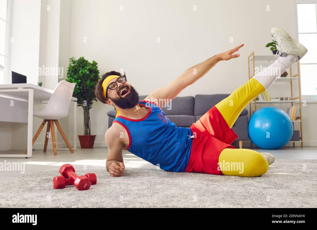 Felice positivo divertente uomo che lavora a casa, facendo laterale disteso gambe solleva e ridendo Foto Stock