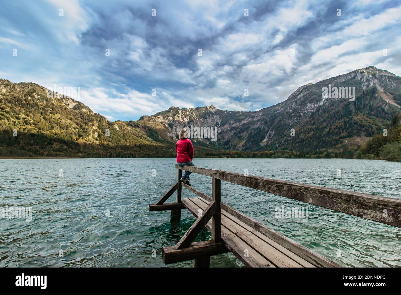 Giovane ragazza che si riposa sul lago di montagna, Austria. Donna che viaggia godendo di vista delle Alpi. Wanderlust concetto di libertà di viaggio. Vacanze estive Foto Stock