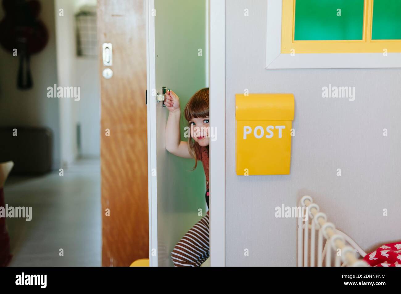 Ragazza che sbirciando attraverso la porta Foto Stock