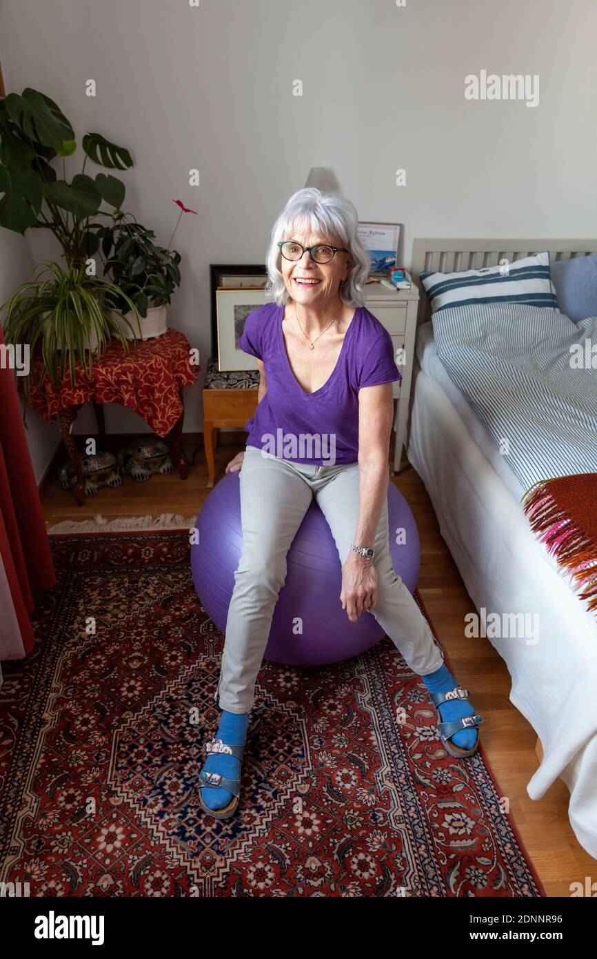 Donna anziana seduta sulla palla di fitness Foto Stock