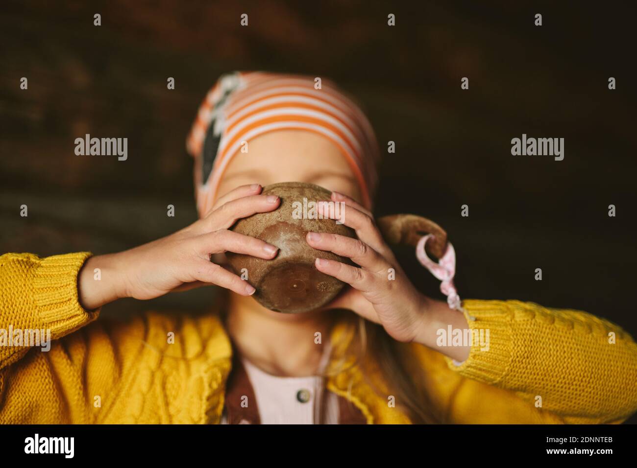 Ragazza che beve da tazza di legno Foto Stock