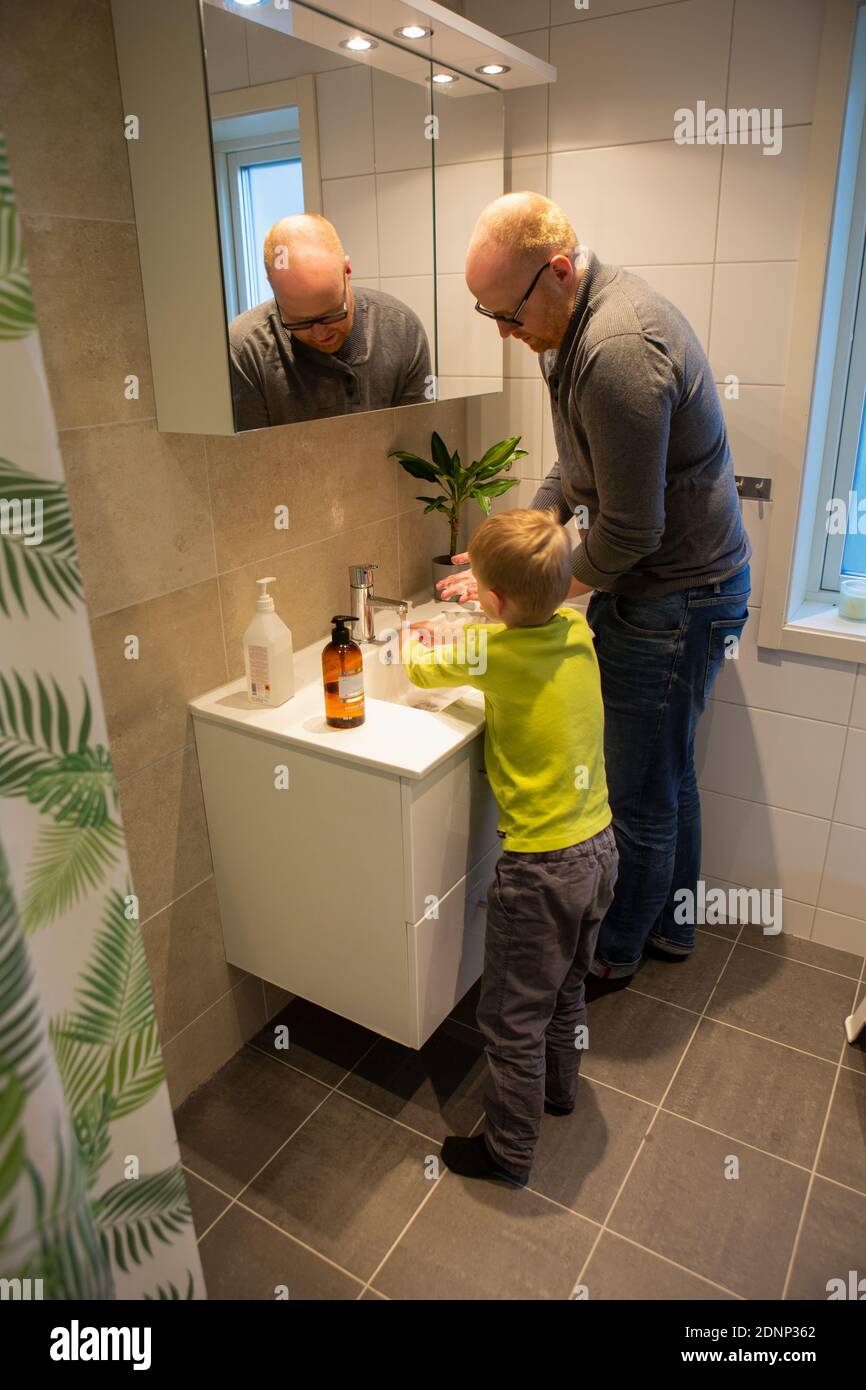 Padre e figlio lavano le mani in bagno Foto Stock